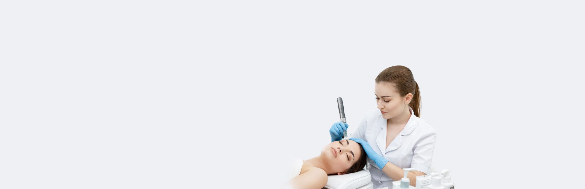 A beauty therapist performs a Dr. Pen microneedling treatment on a client’s forehead